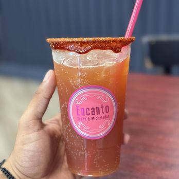 Encanto michelada in a branded cup with a chamoy-and-spice rim and a pink straw